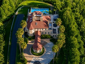 Ein großes, mehrgeschossiges Gebäude mit einem zentralen Innenhof, umgeben von üppiger Bepflanzung und einem Swimmingpool.