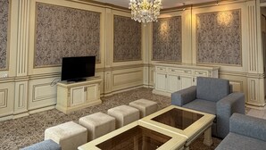 A living room with a television, a chandelier, and patterned wallpaper. - Sky Town Mountain Resort (Chorvoq)