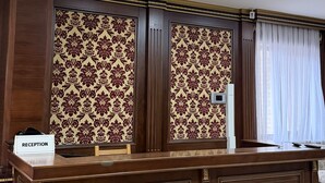 A reception desk with a "RECEPTION" sign, patterned wallpaper, and a window with curtains. - Sky Town Mountain Resort (Chorvoq)