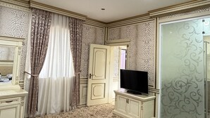 A bedroom with a bed, a TV on a cabinet, a wardrobe, and a door with a mirror. - Sky Town Mountain Resort (Chorvoq)