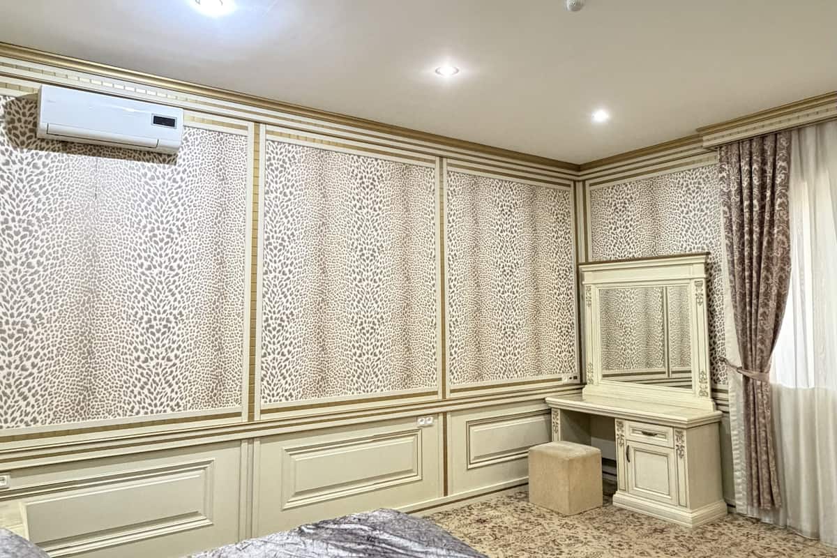 A bedroom with a bed, a dresser, a mirror, and an air conditioning unit.