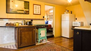 A kitchen with a wooden cabinet, a stove, a refrigerator, and a microwave.