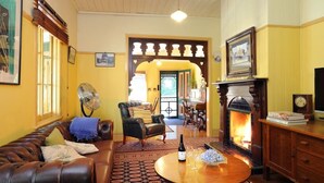 A cozy living room with a fireplace, leather sofa, and a dining area with a table and chairs.