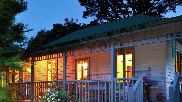 A wooden cabin with a porch, surrounded by greenery.