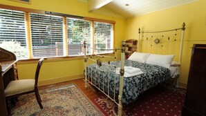 A bedroom with a metal bed frame, a desk, and a chair.