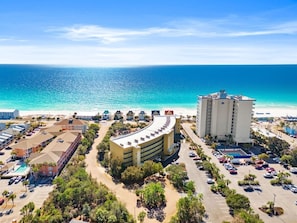 A coastal hotel with a curved building, a pool, and a view of the ocean. - Beach Resort 203 - Retro Luxe Romantic Getaway | Coastal Escape (Miramar Beach)