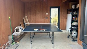 Una mesa de ping pong en una habitación con paredes de madera y una puerta que da al exterior.