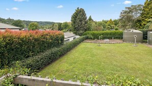 Un jardí ben cuidat amb una tanca ben tallada, gespa i un cobert petit.