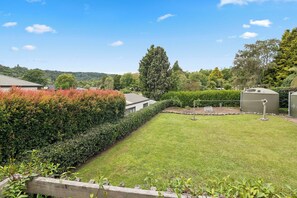 Ein gepflegter Garten mit ordentlich geschnittenem Heckenrand, einem Rasen und einem kleinen Schuppen.