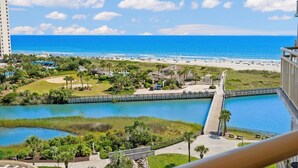 Un resort costero con playa, un puerto deportivo y un parque con senderos y vegetación.