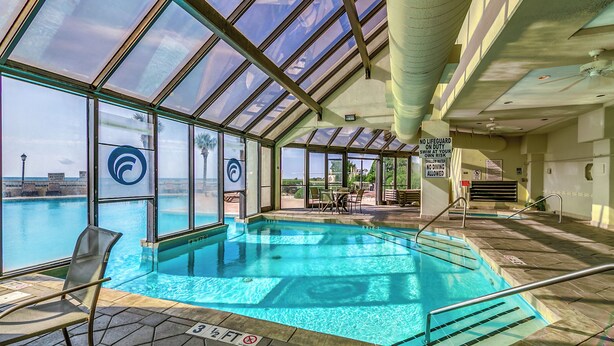 Piscina interior con paredes de vidrio transparente, una estaci ón de socorristas y vistas al océano.