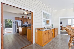 A modern kitchen with wooden cabinets, a stainless steel refrigerator, and a large island with a sink. - 4BR Paradise Oasis with Stunning Ocean Views Near Pebble Beach (Captain Cook)