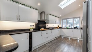 A modern kitchen with white cabinets, a black countertop, and a skylight. - Open Mind Property- 6BR Home, Hot Tub & Free Parking (Fareham , PO15 5RS)