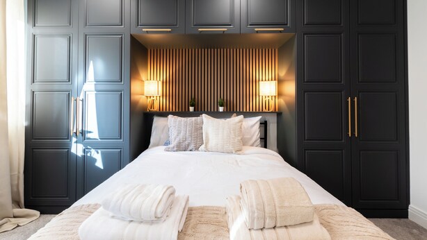 A bedroom with a large bed, dark wooden wardrobe, and two bedside lamps. - Open Mind Property- 6BR Home, Hot Tub & Free Parking (Fareham , PO15 5RS)