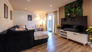 A modern living room with a black sofa, a TV, and a white cabinet. - Open Mind Property- 6BR Home, Hot Tub & Free Parking (Fareham , PO15 5RS)