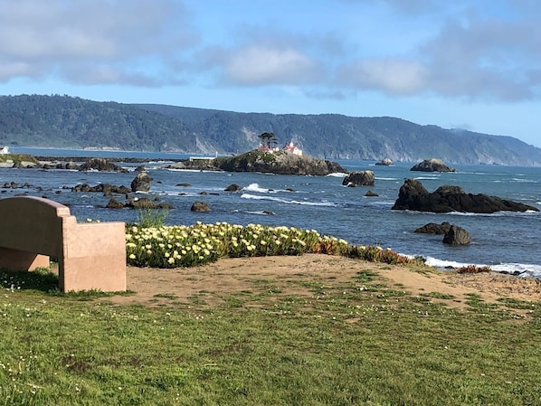 Un paysage côtier avec un phare, une côte rocheuse et des zones herbeuses.