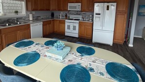 Een moderne keuken met houten kastjes, een witte koelkast, een magnetron en een fornuis.
