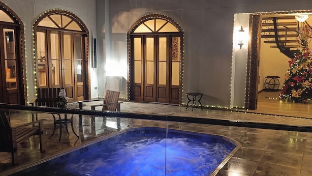 A hotel lobby with a hot tub, wooden doors, and a staircase with a decorated Christmas tree. - Casa Colonial Maria Elena (Pereira)