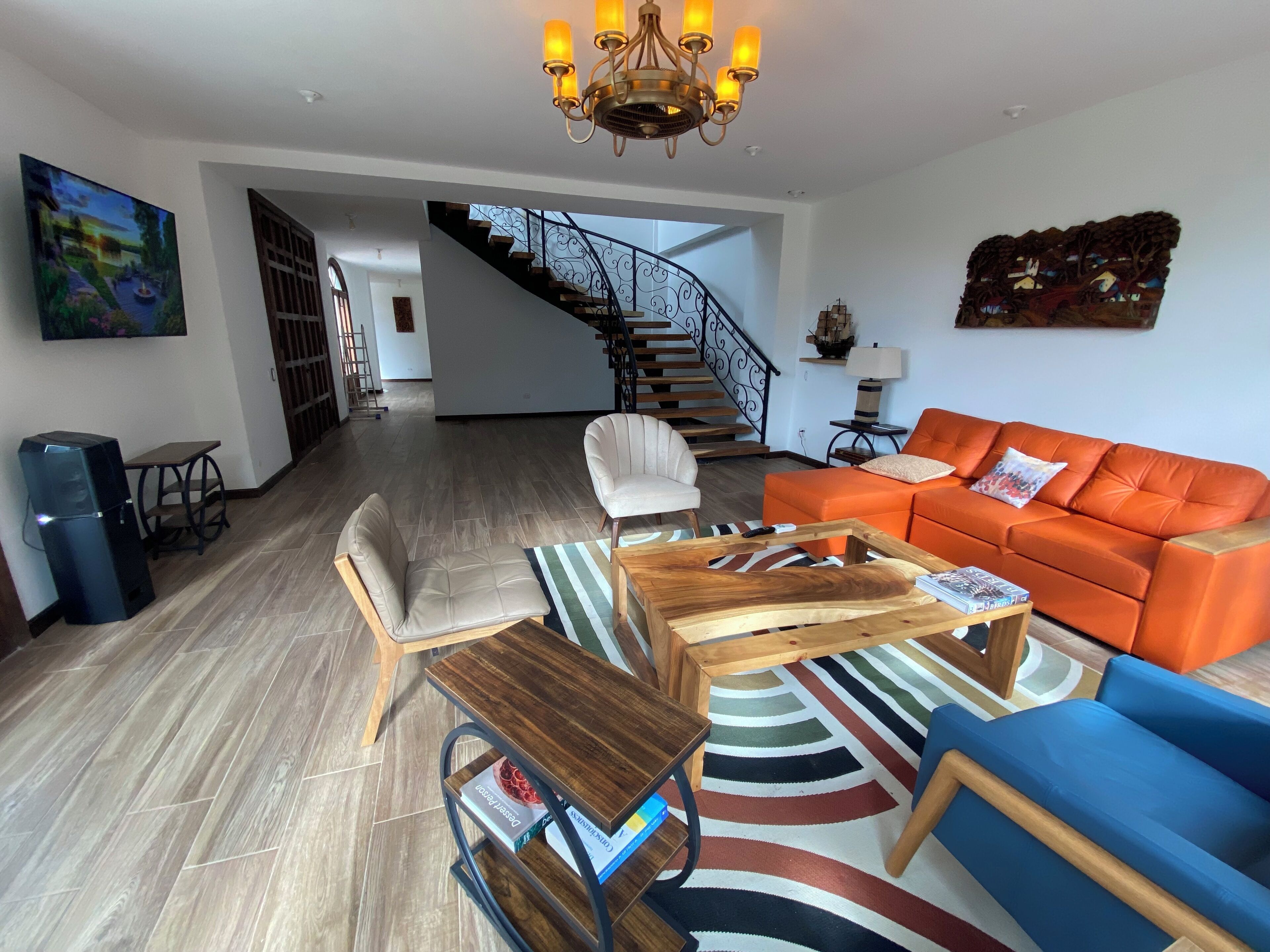A modern living room with a staircase, a sofa, a coffee table, and a bookshelf.