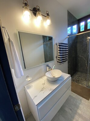 A modern bathroom with a large mirror, a white marble sink, and a glass shower enclosure. - Casa Colonial Maria Elena (Pereira)