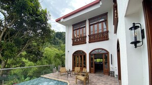 A two-story building with a swimming pool, outdoor seating, and a view of the surrounding greenery. - Casa Colonial Maria Elena (Pereira)
