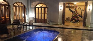 A pool area with a hot tub, wooden doors, and a Christmas tree. - Casa Colonial Maria Elena (Pereira)