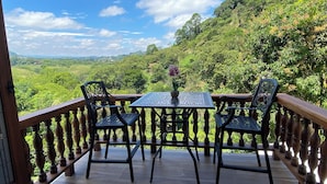 A balcony with a table and chairs, overlooking a lush green landscape. - Casa Colonial Maria Elena (Pereira)