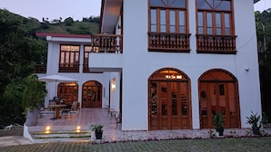 A two-story house with a balcony, large windows, and a paved driveway. - Casa Colonial Maria Elena (Pereira)