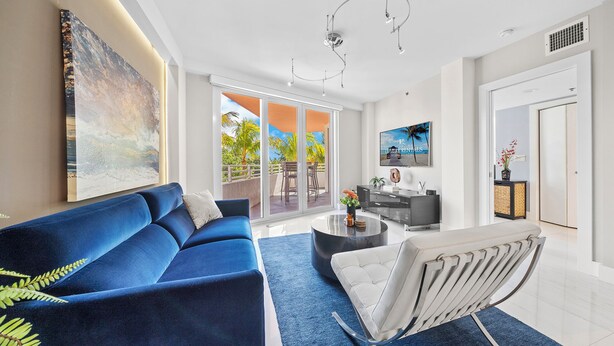 Una sala de estar moderna con un sofá azul, una silla blanca, una mesa de centro y un cuadro grande en la pared.