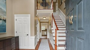 A hallway with a wooden floor, a white door, a staircase with wooden steps and a white railing, and a gray door on the right. - Quiet retreat in Peachtree Corners (Norcross)