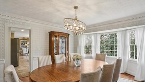 A dining room with a round wooden table, six chairs, a chandelier, and a cabinet with glass doors. - Quiet retreat in Peachtree Corners (Norcross)
