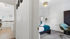 Ein Schlafzimmer mit einem Bett, einem Schreibtisch, einem Sessel und einem Nachttisch.