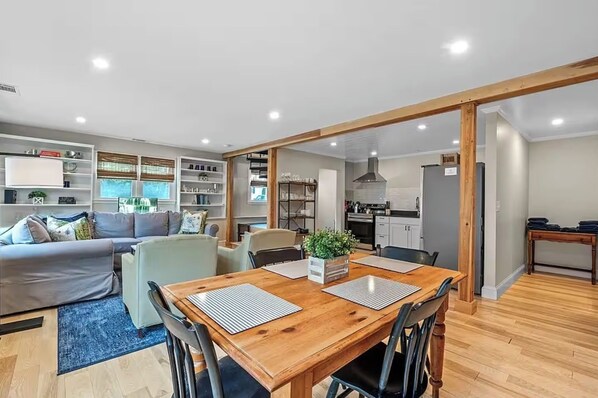 A modern living room with a dining area, wooden flooring, and built-in shelving. - Modern, thoughtfully set-up in heart of town (Marblehead)
