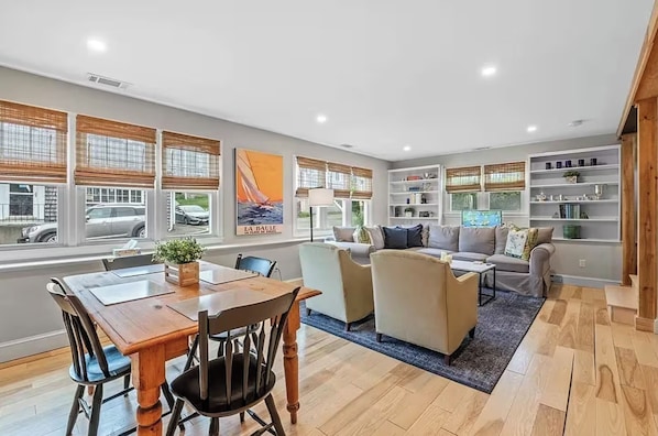 A spacious living area with a dining table, sofas, and a bookshelf.
