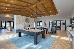 A spacious indoor area with a pool table, stone wall, and wooden ceiling.