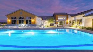 A swimming pool with lounge chairs and a building with multiple windows and doors. - Summerwell by AvantStay (Thermal)