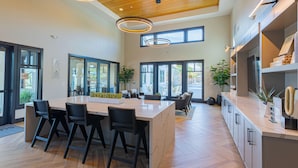 A spacious kitchen with a central island, black bar stools, and a large window providing natural light. - Summerwell by AvantStay (Thermal)