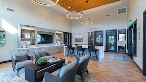 A spacious living area with a modern kitchen, a dining area, and a bar. - Summerwell by AvantStay (Thermal)