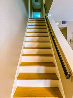 Eine Treppe mit Holzstufen und Geländer, die zu einer Tür oben führt.
