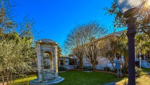 Ein Innenhof mit einem steinernen Gazebo, einem Laternenpfahl und einem gepflegten Rasen.