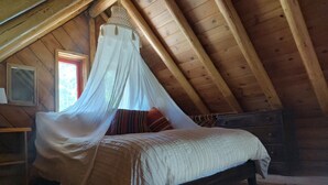A bedroom with a wooden ceiling, a bed with a canopy, a nightstand, and a dresser.