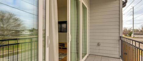 A balcony with a glass door leading to an interior room, a tiled floor, and a metal railing.