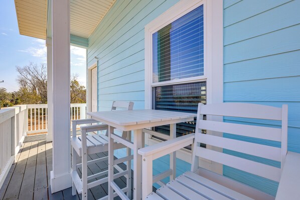 A covered outdoor area with a white table and bench, a window with blinds, and a light blue building. - Deck & Steinhatchee River Views: Family Getaway (Steinhatchee)