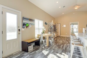 A spacious kitchen with a wooden floor, a dining area with a bench and chairs, and a bar area with stools. - Deck & Steinhatchee River Views: Family Getaway (Steinhatchee)