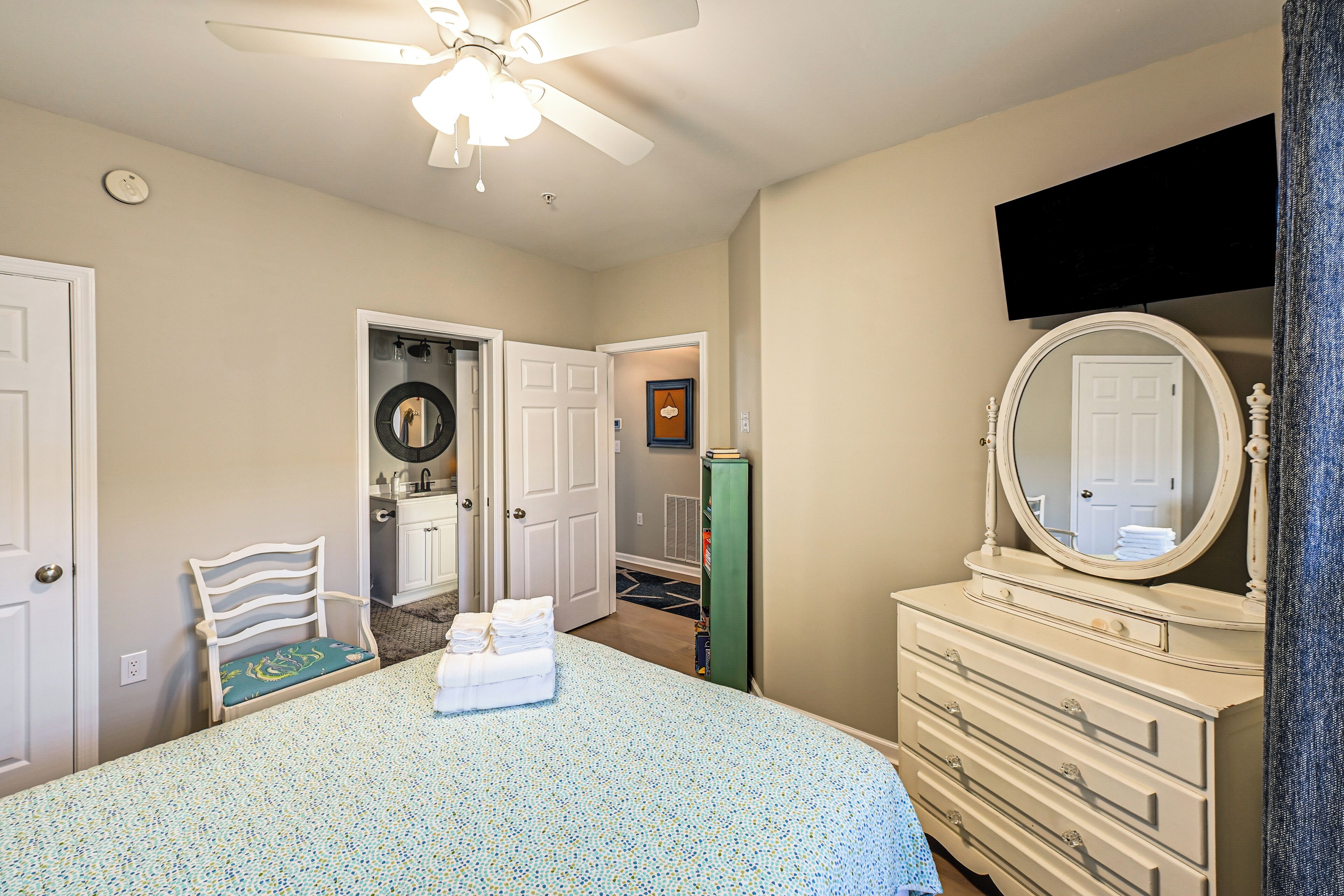 Un dormitorio con cama, cómoda y ventilador de techo.