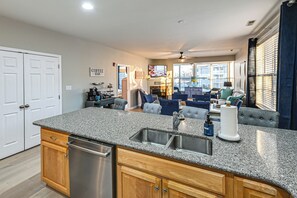 A modern kitchen with granite countertops, stainless steel appliances, and wooden cabinets. - Bay-n-Beach! Comfy Coastal Condo in Lewes! (Lewes)
