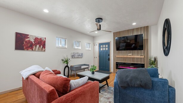 A living room with a sofa, a blue armchair, a coffee table, a TV, and a door. - Stunning! Modern with original hardwood! (Sioux Falls)