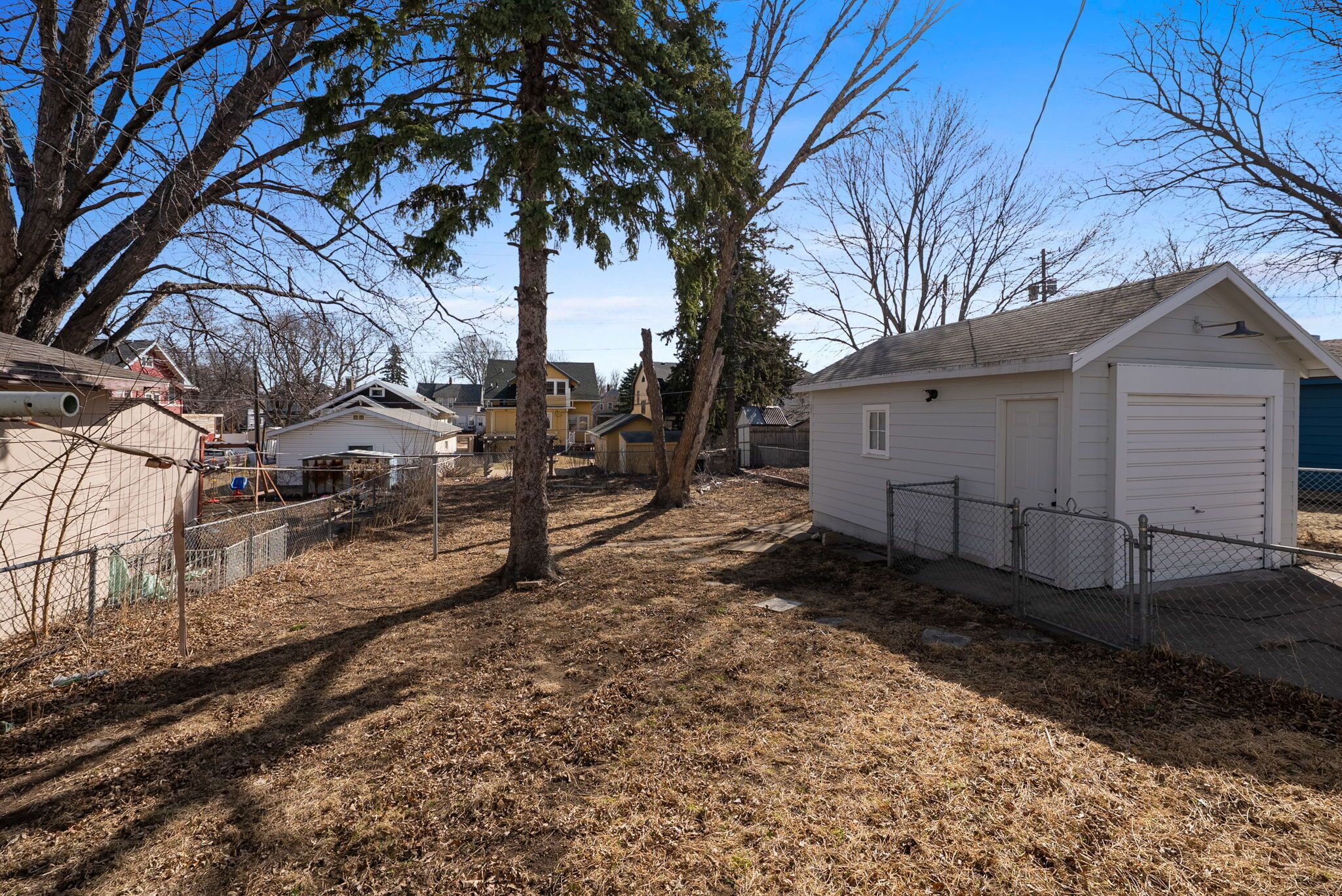 A residential area with detached houses, a fenced yard, and a garage.