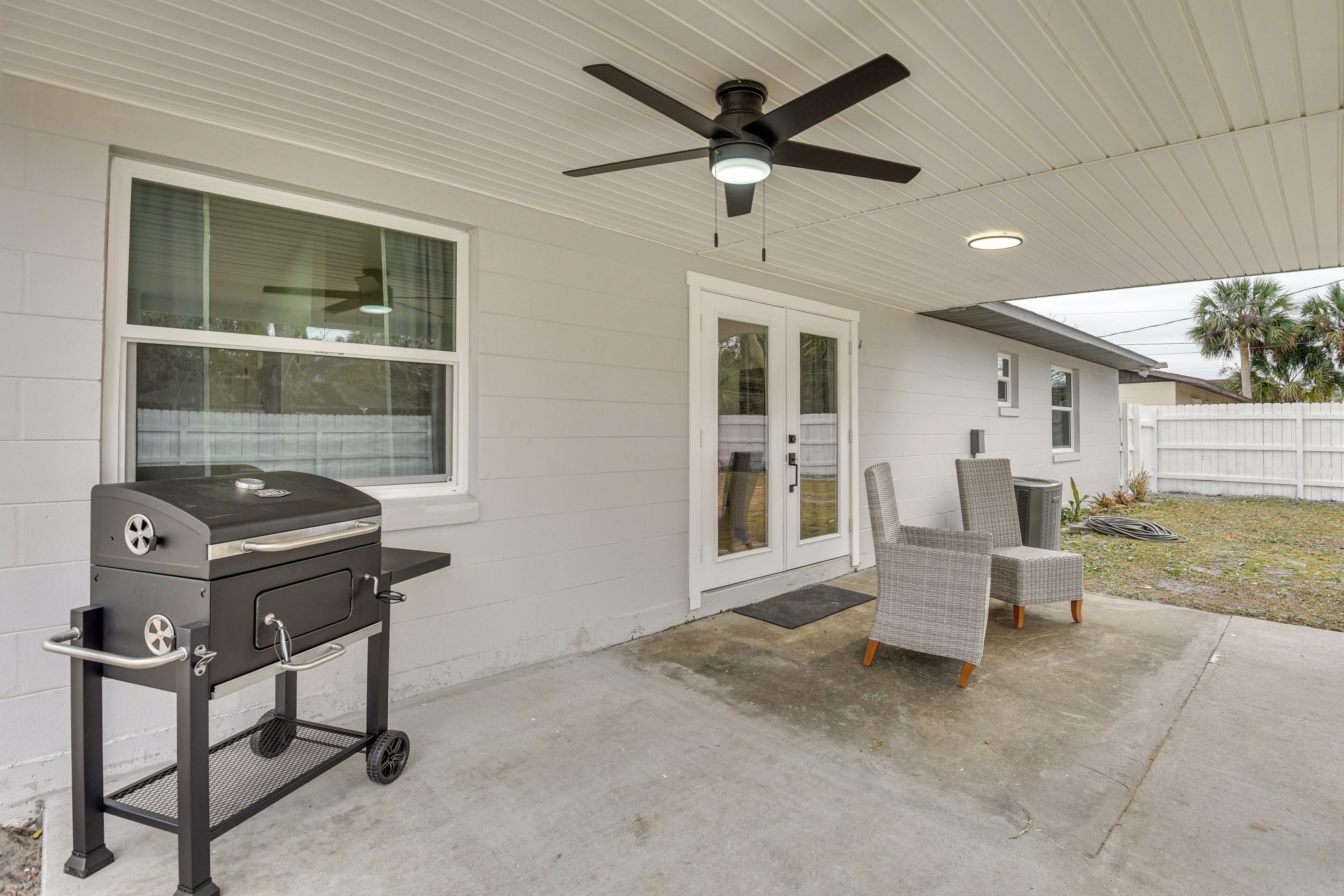 A patio with a grill, a ceiling fan, and outdoor seating.