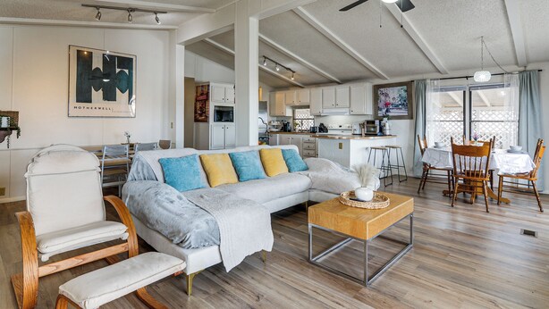 En rummelig opholdsstue med sofa, gyngestol og spisebord med stole.